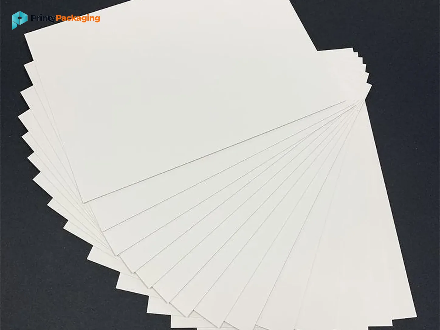Stack of white paperboard sheets on a dark surface